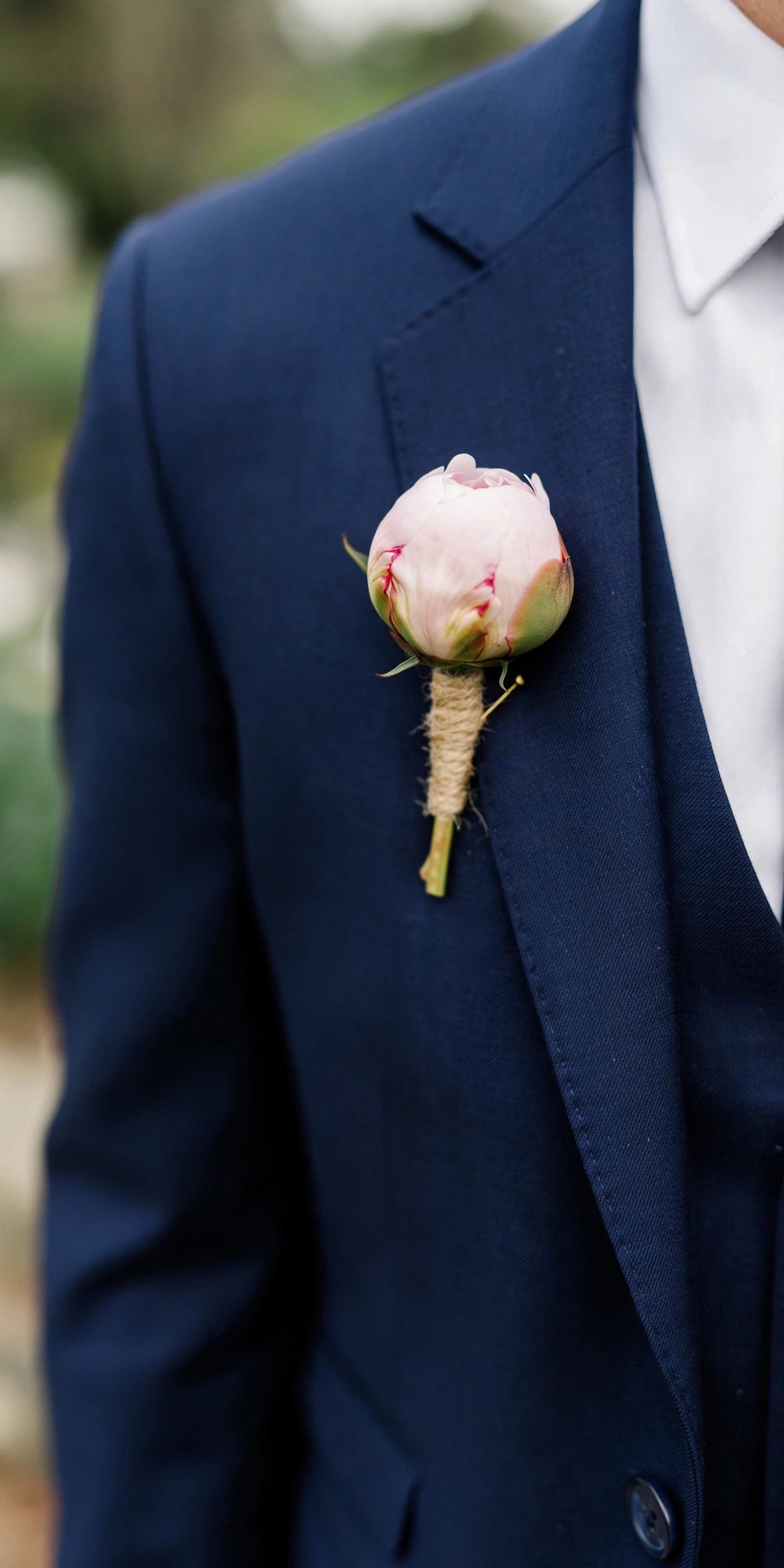Single peony bud wedding boutonniere on a navy suit