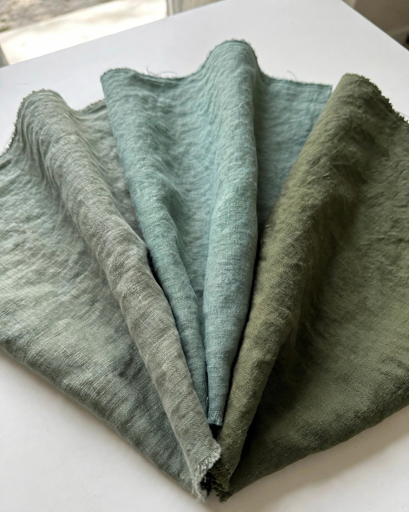 Green fabric swatches compared in natural daylight for bridesmaid dresses